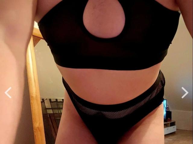 Johny13313-hot in black sheer lingerie, showing their tits through a cutout, and wearing mesh panties, with a visible, bare, and slightly tan lower belly and thighs.