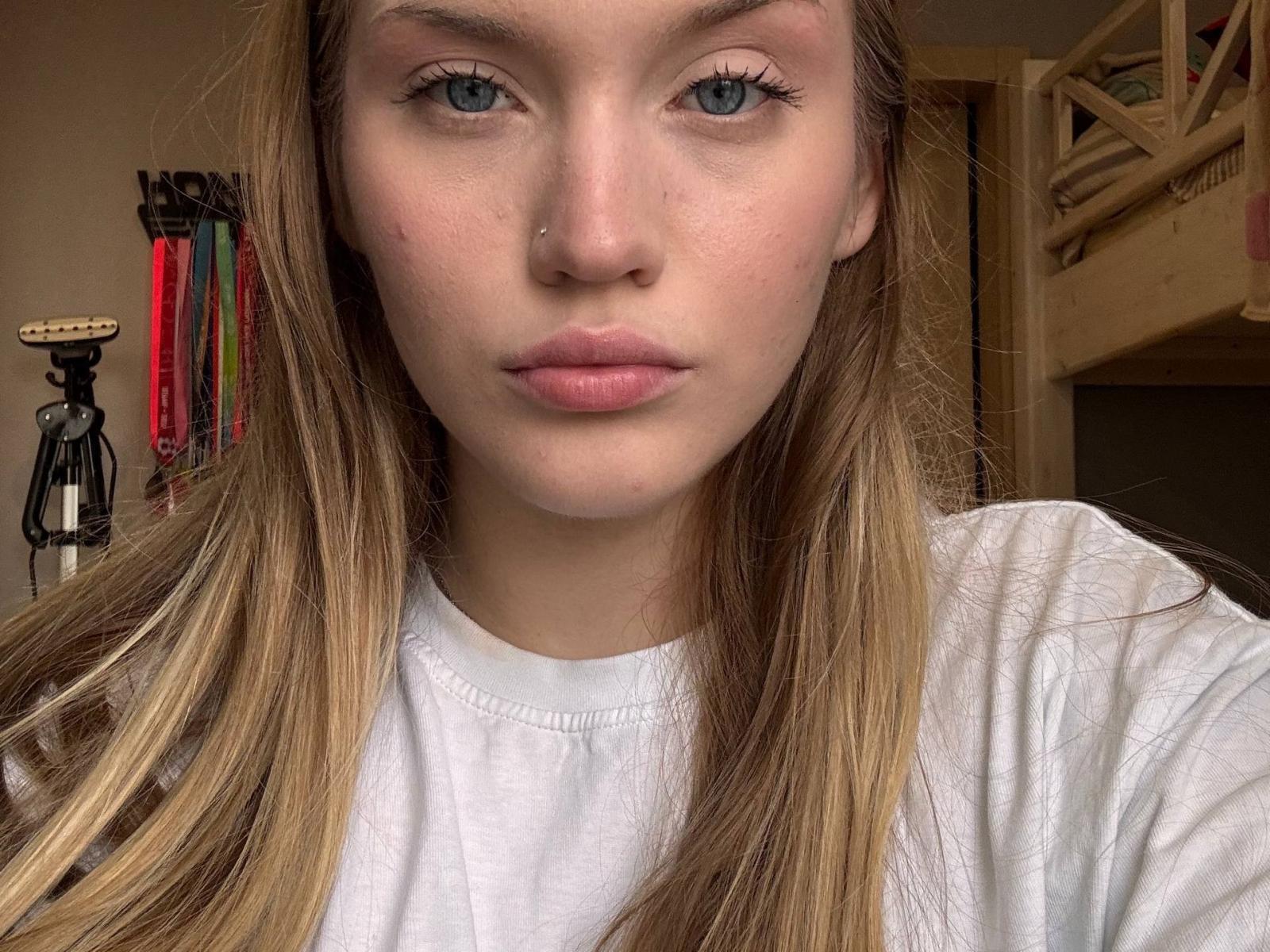 Emmy Thruthley ha gli occhi azzurri, la pelle chiara e i capelli lunghi biondi. Indossa una camicia bianca, ha un piccolo piercing al naso e le labbra leggermente rosse..