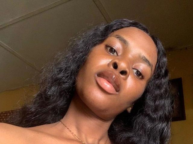 Nastybitch-hot has dark, curly hair, shiny brown skin, full pink lips, and a cute, slightly open-mouthed, up-close selfie with a subtle smile.