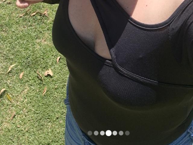 PaulaAnd's black tank top shows a noticeable, dark, circular bruise over her tits, with her blue jeans and green grass in the background.