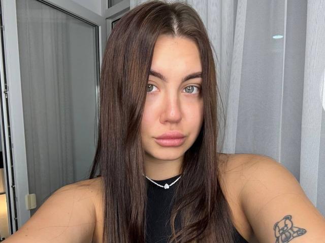 Ines Gueningsman a de longs cheveux bruns, des yeux verts et un tatouage sur son bras droit. Elle porte un haut noir avec un collier blanc. Ses seins sont petits..