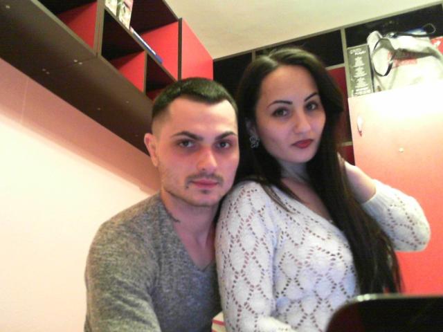 Bonnie69clyde, con i capelli corti e scuri e un baffo, che indossa una camicia grigia, è seduta accanto a Bonnie69clyde, con i capelli lunghi e scuri, che indossa una maglietta bianca a fantasia, in un caffè..