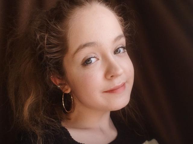 MandiBouie ha la pelle chiara, i capelli castani ricci, gli occhi verdi e un sorriso delicato. Indossa grandi orecchini a cerchio e una maglietta nera. Il suo viso è leggermente rivolto di lato..