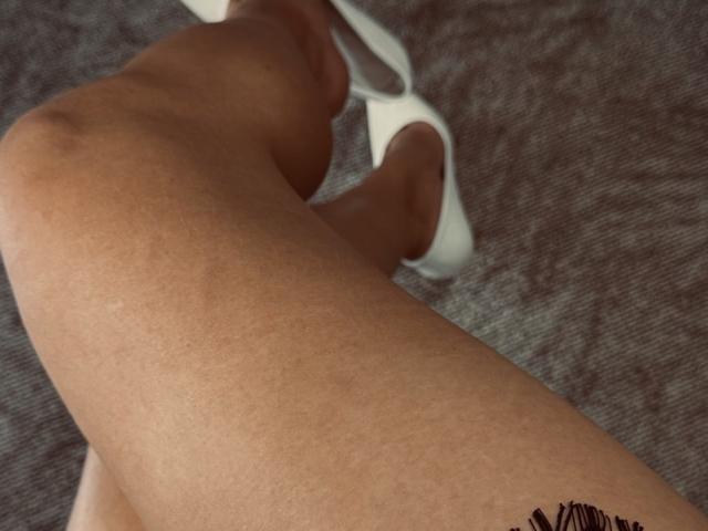 MissiSofiya's tan legs with white high heels, showing smooth skin and slight muscle definition, positioned in a slightly bent, relaxed stance.