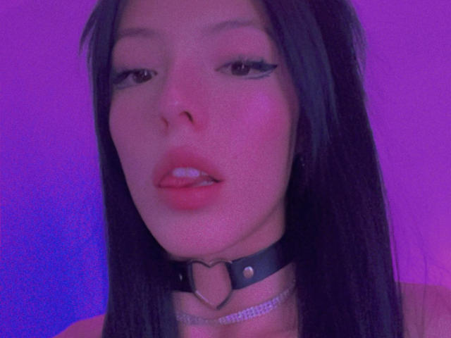 AizenMyoo with long black hair, pink-tinged face, wearing a black leather choker with a heart-shaped metal ring, and a silver chain, has slightly parted pink lips.