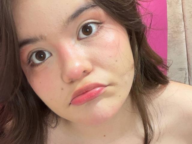 AlexaMissFortune has pinkish-red lips, brown eyes, and a slightly pouty face with a few small moles. She has light skin and brown, wavy hair. Her nose is small.