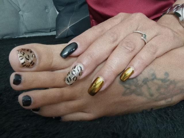 LailaCastillo's feet with painted toenails: black, leopard print, gold, and white pattern. She's wearing a silver ring on her right hand with a tattoo on her left ankle.