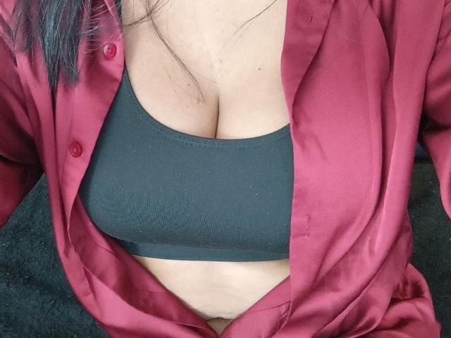 LailaCastillo's chest, showing large tits in a black sports bra, covered by an open red satin shirt. Her skin is light, and she has black hair.