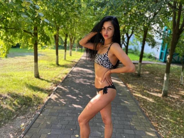 EvaClarkX se tient dans un parc, vêtue d'un soutien-gorge à imprimé léopard et d'un string noir, avec de longs cheveux noirs, un corps mince et tonique, et une pose assurée..