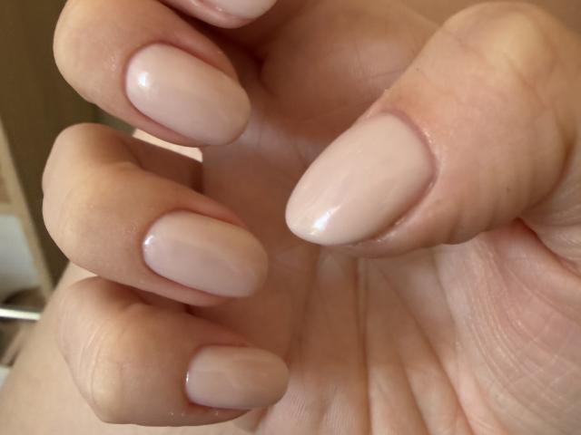 De handen van KarKutie, met glanzende, nude-roze, amandelvormige nagels, laten goed verzorgde vingers en een gladde, lichte huidskleur zien. Haar nagels zijn netjes gevijld en glanzend..