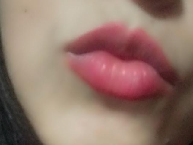 BelaDeimons' puffy pink ass-kissing lips are centered in the image, with a slightly blurred background, highlighting their glossy, full, and shiny pink lip color.