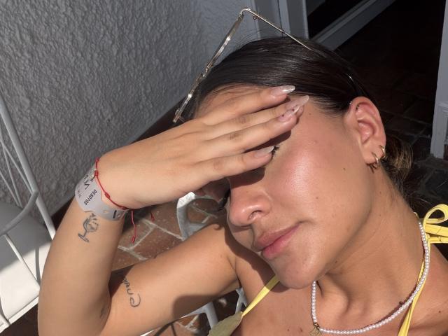 ThaliaAres ha la pelle olivastra, i capelli castani e un nasino piccolo. È con gli occhi socchiusi a causa della luce del sole, con una mano che si copre gli occhi. Indossa un top da bikini giallo, una collana di perle e un braccialetto..