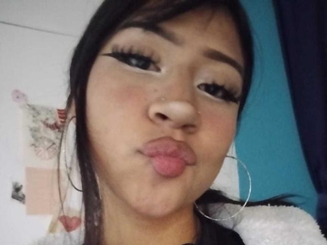 BonnieBodn, met volgezwollen lippen, draagt opvallende zwarte eyeliner, een neusring en grote oorringen. Ze heeft donkerbruin haar en een lichtbruine huidskleur en maakt een grappig gezicht..