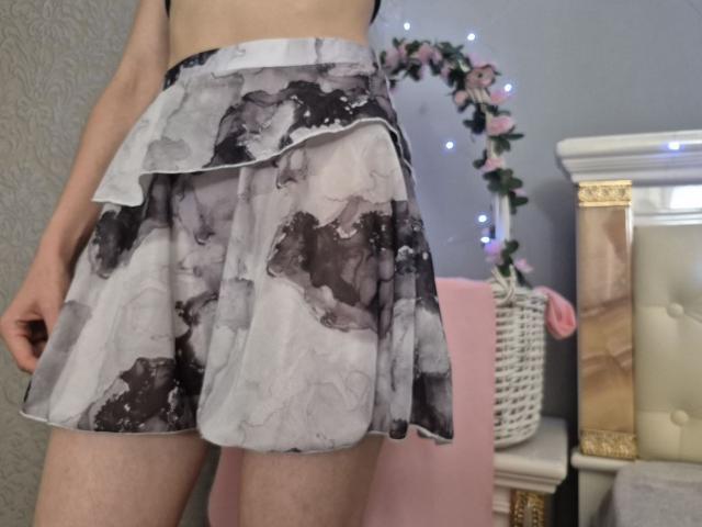 Seliina's ass in a short, black-and-white watercolor-patterned skirt, standing with a slight turn, showing her upper thighs and part of her back.