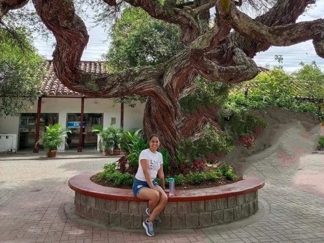PauletteLoveX, mit mittelgroßer Brust und einem hübschen Hintern, sitzt auf einem roten Ziegelkreis, trägt ein weißes T-Shirt und blaue Shorts, unter einem riesigen, verdrehten Baum..