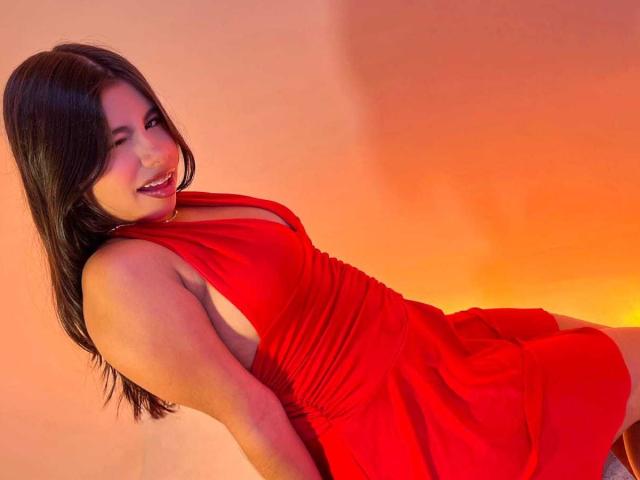 CelesteMorel in a red dress, smiling, showing her ass, with her tits slightly visible, leaning back, brown hair, red lighting, and a cute, sexy look.