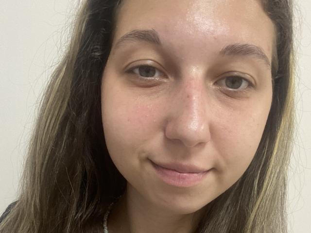 Sanella's face with light brown skin, small nose, slightly upturned lips, and brown eyes. She has long, dark brown hair with blonde highlights, and a subtle smile.