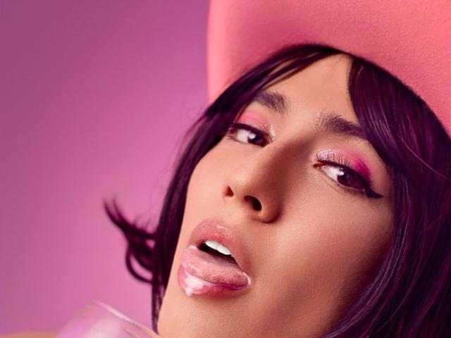 EllieCherry has dark purple hair, pink eyelids, and shiny pink lips with white gloss, wearing a pink beret, looking up with slightly open mouth.