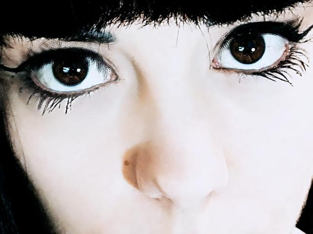 OrianaLaFrancaise's face, focused on her large brown eyes with thick black eyelashes, pale skin, and black eyebrows, showing a slight nose and full lips.