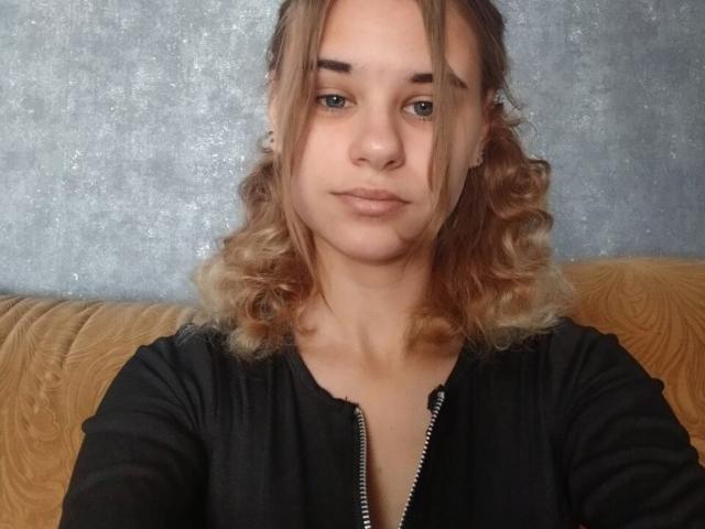 Brittaney Jecklin tem cabelos loiros ondulados, olhos azuis e um leve sorriso. Ela está vestindo uma camisa preta com zíper, e suas nádegas não estão visíveis na imagem..