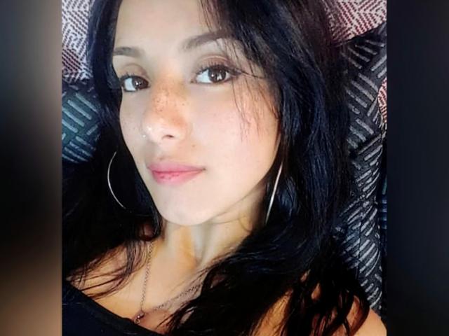 Hotcaroline33 ha i capelli neri, gli occhi marroni, delle lentiggini sul naso e indossa una maglietta nera con una spalla scoperta, grandi orecchini a cerchio e una collana..
