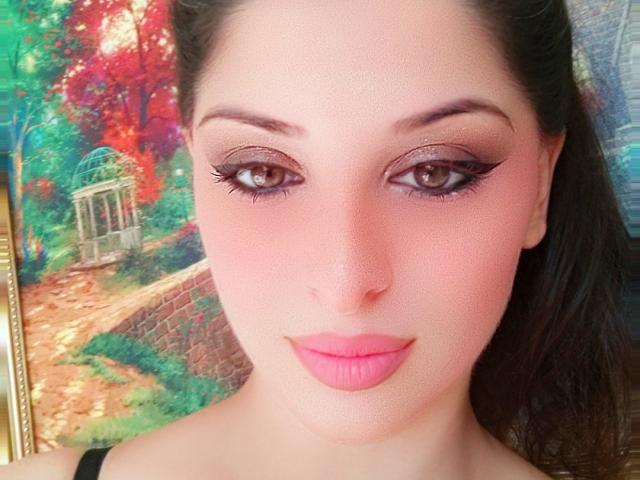 ScarletOra ha un rossetto rosa, un eyeliner scuro e occhi marroni. Il suo viso è leggermente arrossato con una tonalità rosata, e ha i capelli neri e lisci. Il suo seno non è visibile..