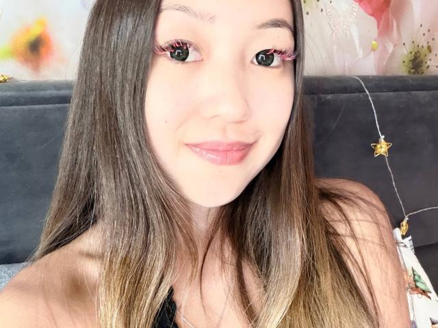 RenyLime has long brown hair, pink eyelashes, and a slight smile, showing off her pouty ass-kissing lips, with a cute star-shaped necklace on the right.