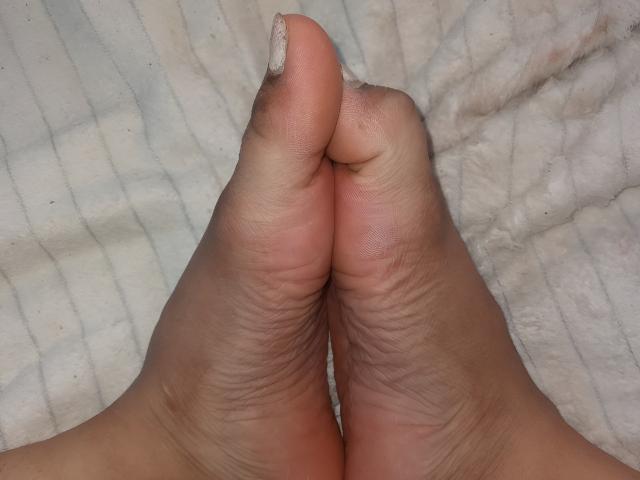 ArianithaXox's soles and toes are pressed together, showing wrinkled skin and a slightly dirty, pinkish toe with a glittery nail polish on the big toe.