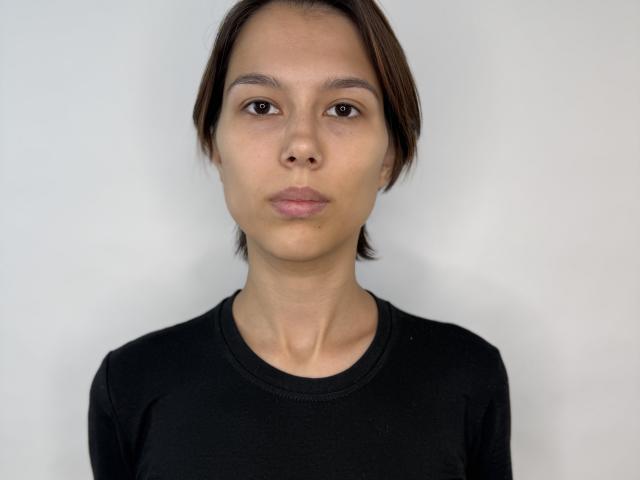 Magali Fissori heeft kort bruin haar, bruine ogen en een neutrale uitdrukking. Ze draagt een zwart shirt, en haar kleine borsten zijn lichtelijk zichtbaar. Eenvoudige witte achtergrond..