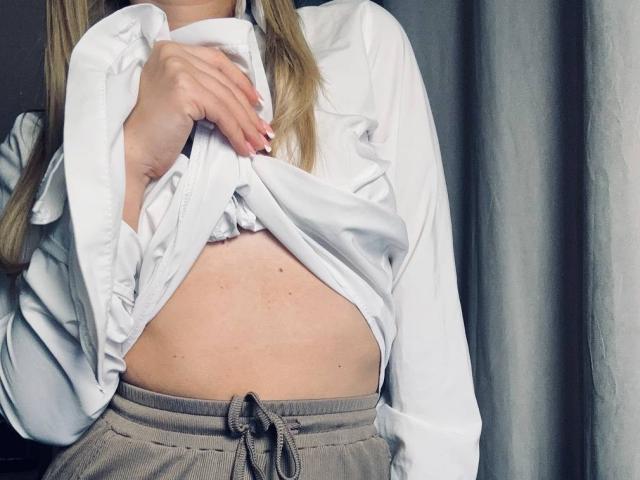 BalletSwan's white shirt is lifted to show her flat, slightly freckled midriff. She's wearing gray sweatpants with a tied waistband. Her hand has white-painted nails.