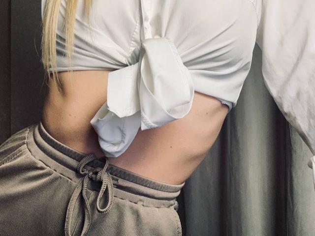 BalletSwan's white shirt tied in a knot, exposing her flat midriff and lower belly, wearing gray sweatpants with a drawstring, showing a slight tan line.