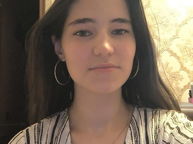 TillieOverall ha lunghi capelli castani, pelle chiara e indossa piccoli orecchini a cerchio. Indossa una camicia a righe e ha un'espressione neutra. Il suo naso è leggermente all'insù..