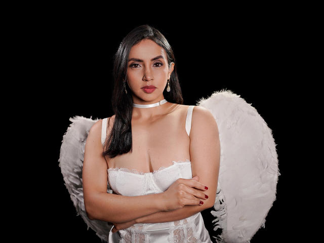 BelladonnaLips with white angel wings, black hair, white choker, and white lace-up corset, arms crossed, red nail polish, looking serious, black background, full body, sexy.