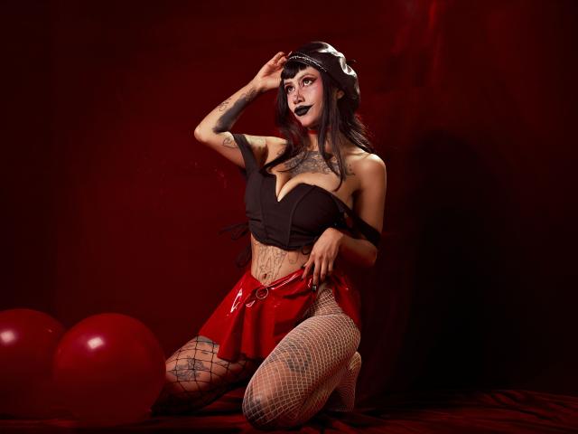 NyxVega, goth chick with black lipstick, tattoos, black tube top, red skirt, fishnet stockings, kneeling, hand on head, red balloons, dark red background, sexy, dark makeup, black hair.