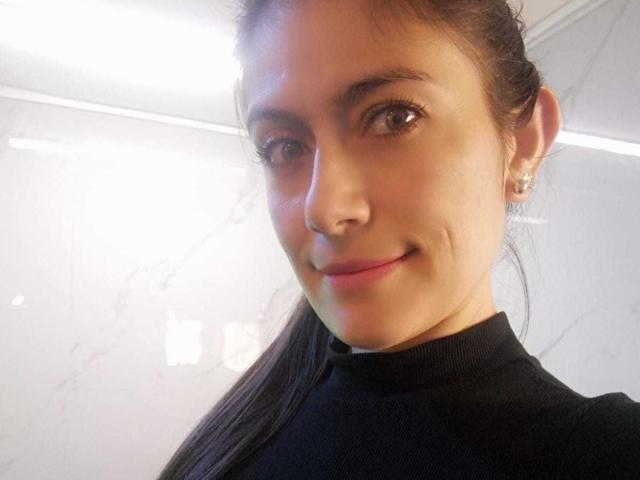 Sara Graham ha un sorriso carino, occhi marroni e una piccola fossetta sulla guancia destra. Indossa un maglione nero a collo alto e i suoi capelli castani sono raccolti in una coda di cavallo..