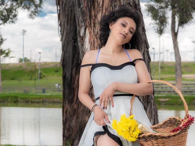 VioletaSwitch with curly black hair, light skin, and small tits, wearing a white dress with black trim, leaning against a tree, holding a basket with yellow flowers.