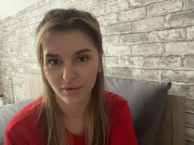 ElanaFalencki with straight brown hair, red shirt, and slight smile, looking at camera, showing her face and upper chest. Her nose is pierced.