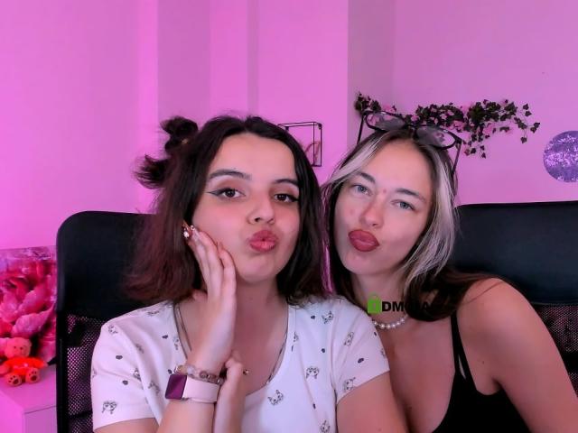 LiaOneMia with dark brown hair in puffs, kissing lips, white shirt, hand on cheek. LiaOneMia with blonde hair, black top, green choker, tongue out, black chair.