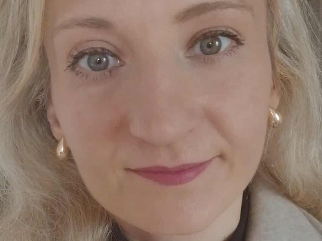 ViolettaLoves ha la pelle chiara, gli occhi azzurri e i capelli biondi con leggere onde. Indossa orecchini di perle e rossetto rosa, e sorride dolcemente alla fotocamera..