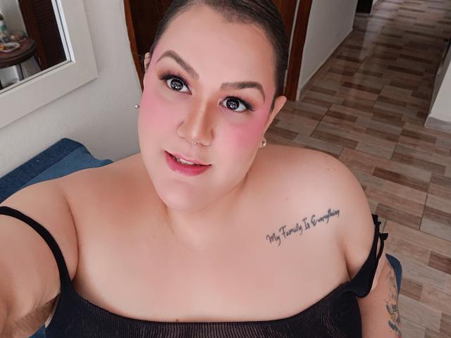 GiiannaMorrys has pink blush, blue eyes, and a nose ring, with black straps on her shoulders and a tattoo on her right boob that says "My treasure is found."