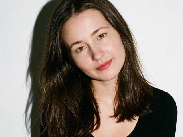 RosalindCutsinger ha i capelli castano di media lunghezza, la pelle chiara e un leggero sorriso. Indossa una maglia nera, con un'ombra sul lato sinistro del viso..