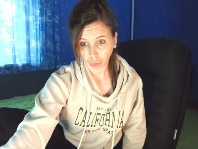 LoveisHt tiene una cara linda y con los labios fruncidos, con ojos verdes, y lleva una sudadera beige de California y pantalones negros, sentada en una silla negra, mirando a la cámara..