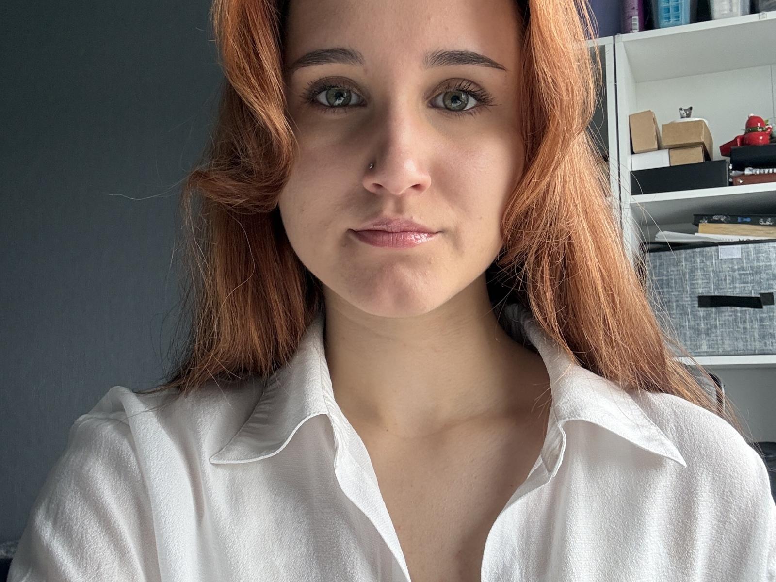 Gail Harmeson a les cheveux roux, les yeux verts, un piercing au nez, et porte une chemise blanche avec un léger col. Ses lèvres roses sont légèrement entrouvertes..