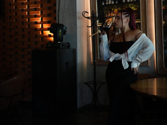 Niferttiti with purple hair, off-shoulder white shirt, black dress, holding wine glass, standing by window, brick wall, dark room, side profile, curvy, large tits, sexy.