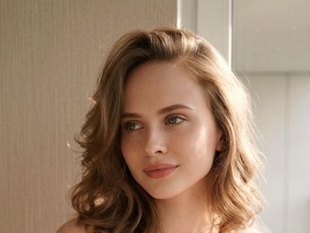 VictoriaAlarie has light brown wavy hair, green eyes, and a subtle smile with a natural makeup look, showing her pretty tits and a cute face.