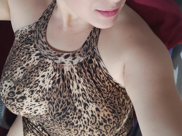 AlexaHotSeins ha la pelle chiara, le labbra rosa e indossa un top a halter con stampa leopardo, che mette in mostra il suo seno prosperoso e un po' del suo fianco. È leggermente inclinata in avanti..