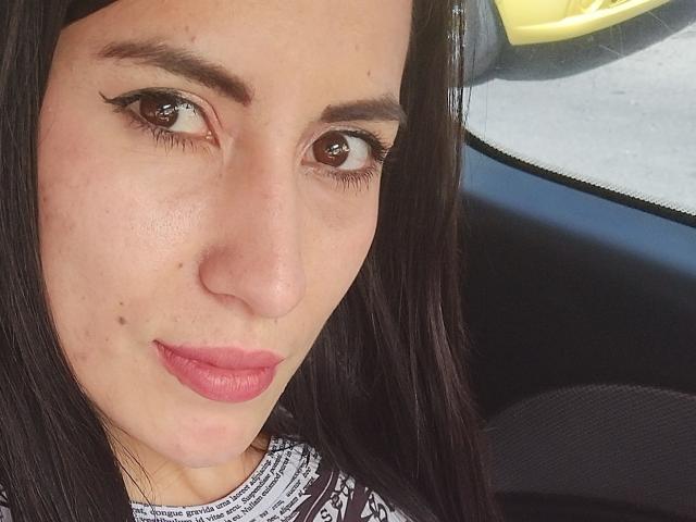 SofiaAnal heeft bruine ogen, zwarte eyeliner, roze lippenstift en een klein sproetje op haar rechterwang. Ze draagt een top met een wit en zwart patroon, en heeft zwart haar..