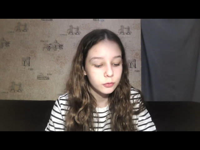 FarrahShulthess has wavy brown hair, pale skin, and is wearing a striped shirt with her eyes closed and lips slightly parted. She looks cute and relaxed.
