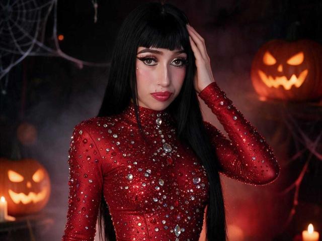 Boorbuja with long black hair, wearing a red, sparkly dress, hand in hair, looking at camera, Halloween jack-o'-lanterns, candles in background, dark, spooky setting. Boobs, ass covered.