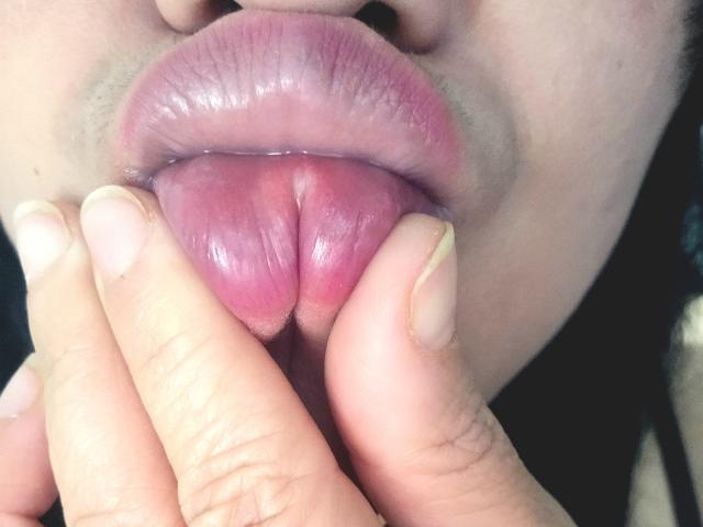 La langue rose de Viviana Thompson est visible, et ses doigts tirent doucement sur sa lèvre inférieure. Ses ongles sont soigneusement coupés, et ses lèvres sont légèrement brillantes..